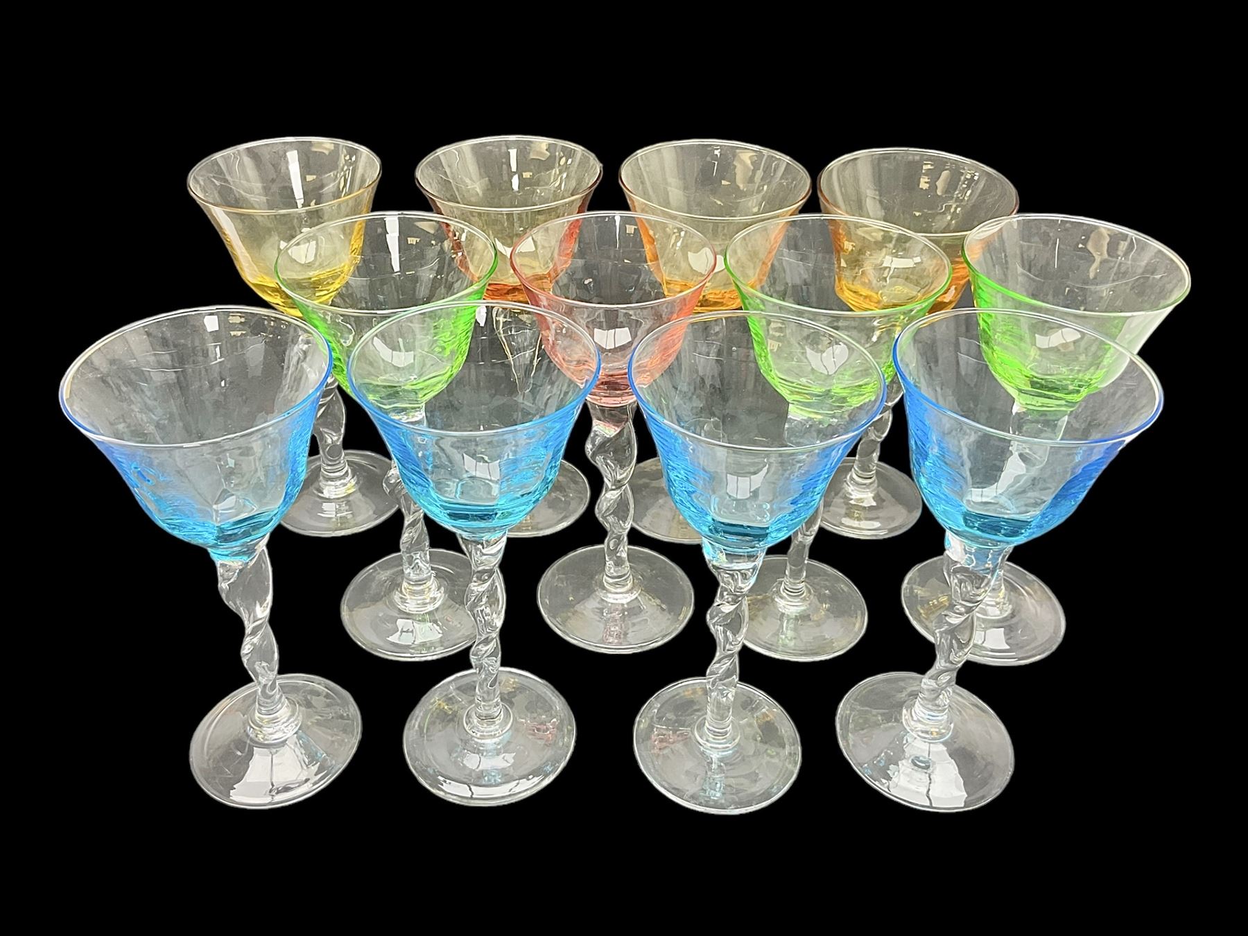 Ten coloured Adriana wine glasses by Abigails, to include blue, green, pink and yellow examples, each with part faceted bowl and twist stems, together with two similar orange examples with pulled stems, H24cm