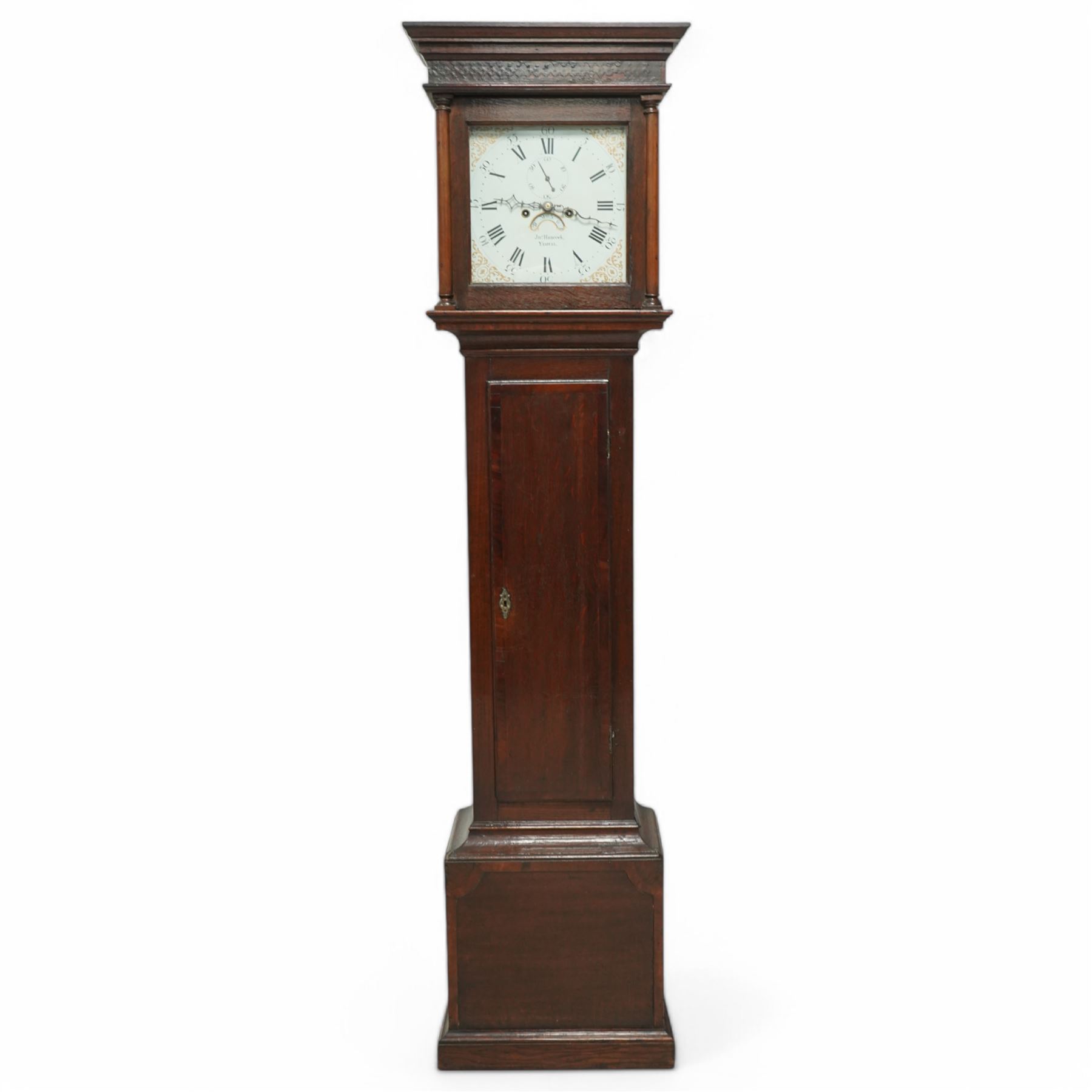 John Hancock of Yeovil (Sommerset) - oak cased 8-day longcase clock c1810, with a flat topped pediment, blind frieze and broad cornice, square hood door with attached wooden pilasters and capitals, long trunk door on a square plinth with applied skirting, painted dial with steel hands, gilt painted spandrels, Roman numerals, minute track and five-minute Arabic's, with seconds dial and date aperture, dial pinned via a falseplate to a rack striking movement, striking the hours on a bell. With weights and pendulum.