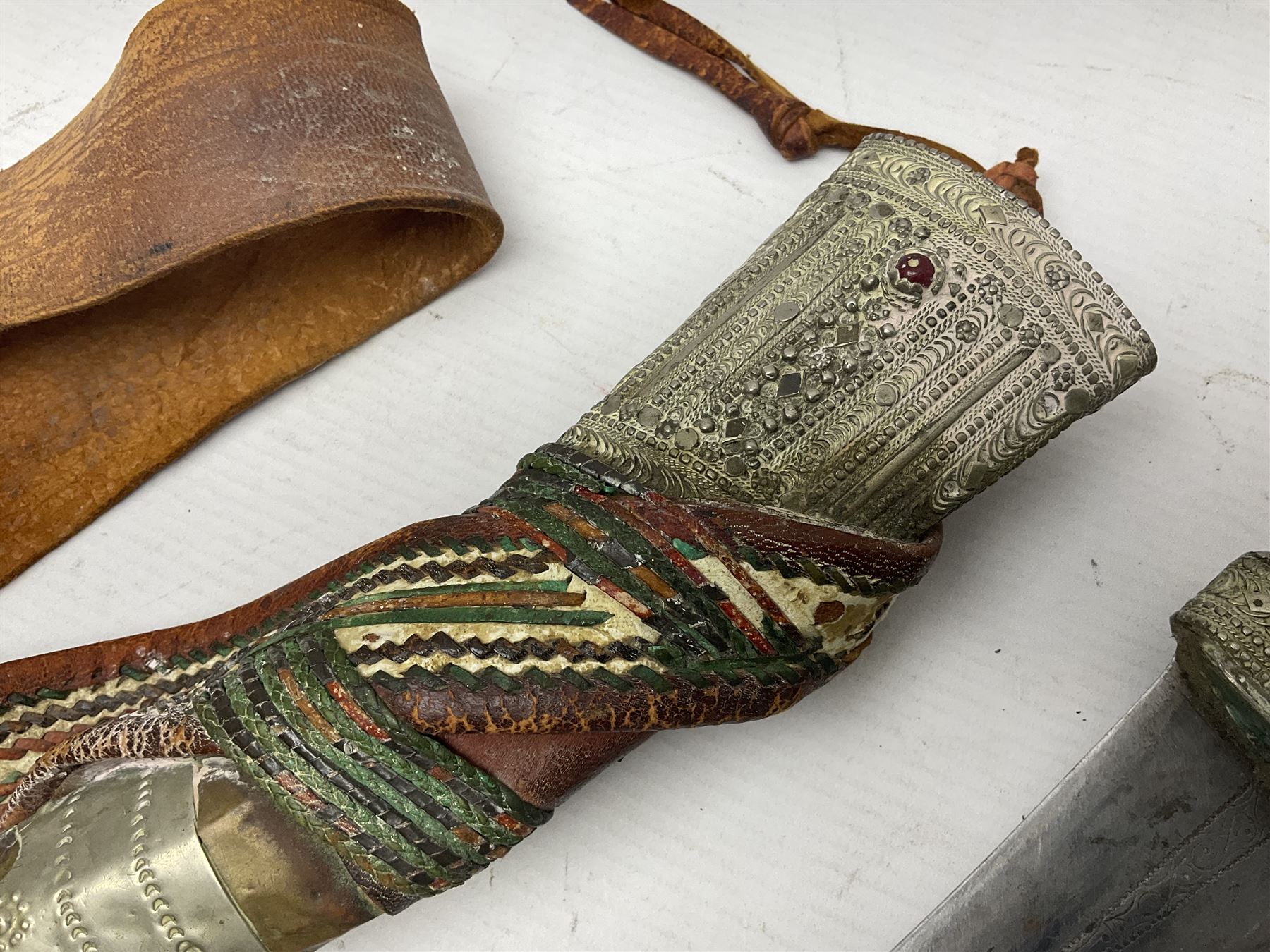 Saudi Arabian khanjar dagger with 29.5cm curving double edged  steel blade; white metal and copper mounted horn grip; in white metal mounted brass and leather scabbard incorporating embroidered leather wearing strap