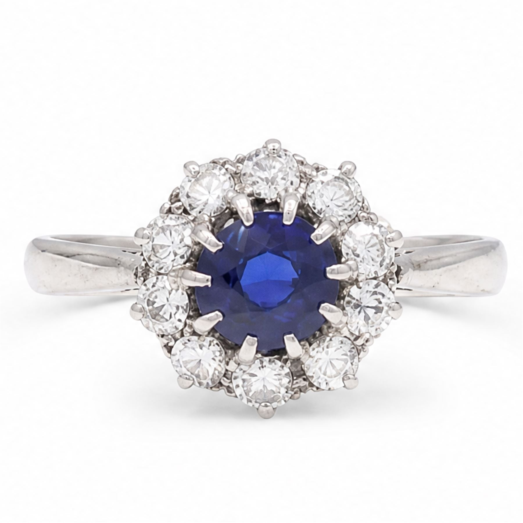 Platinum sapphire and diamond cluster ring, single round cut sapphire of approx 0.85 carat, surrounded by ten round cut diamonds, total diamond weight approx 0.40 carat