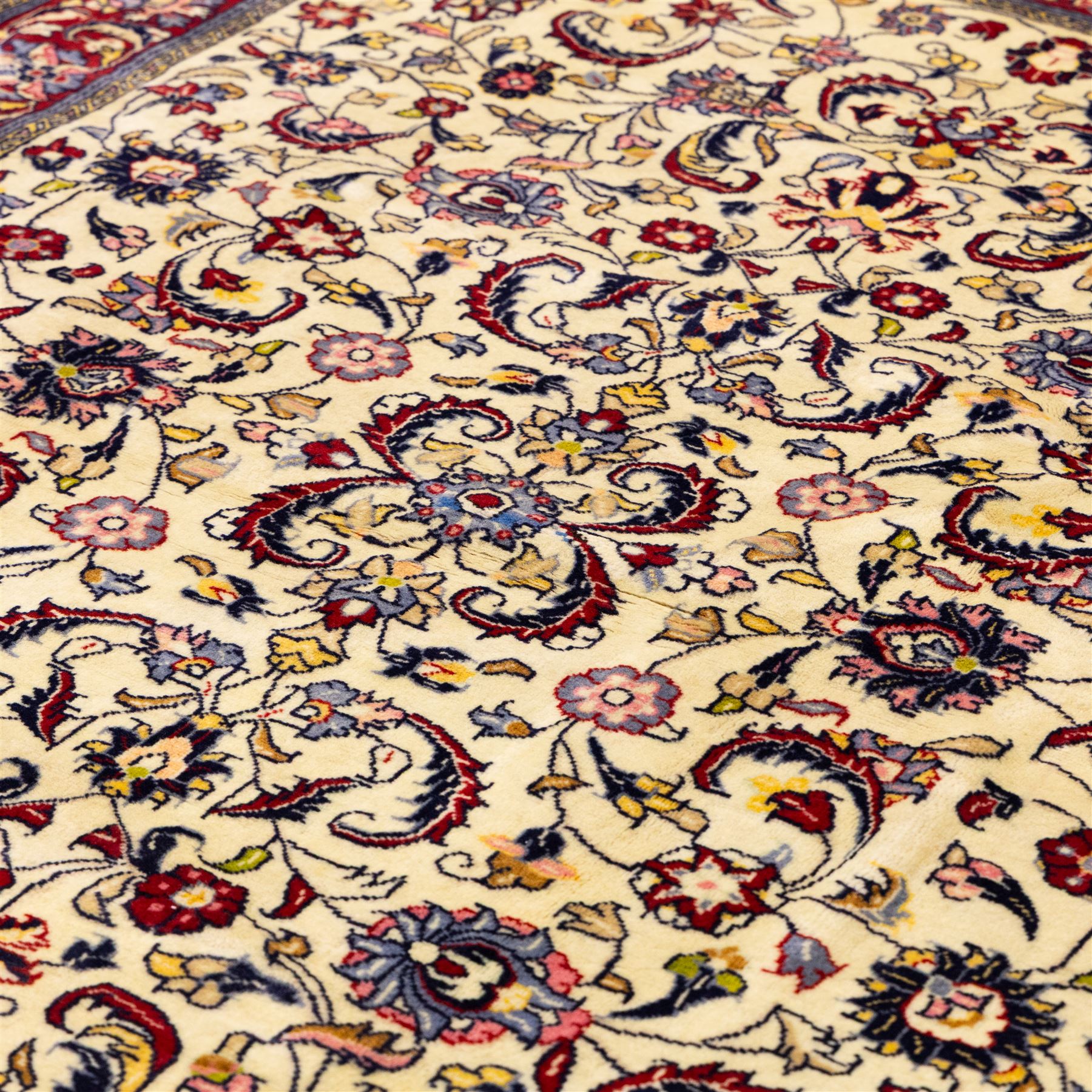 West Persian Sarough hand-knotted rug, ivory field decorated with finely drawn symmetrical lattice of scrolling vines, palmettes and flowering sprays issuing from a subtle central medallion, enclosed by a broad madder-red border of stylized palmettes and foliate vine ornament between multiple guard stripes, with cotton fringe ends 