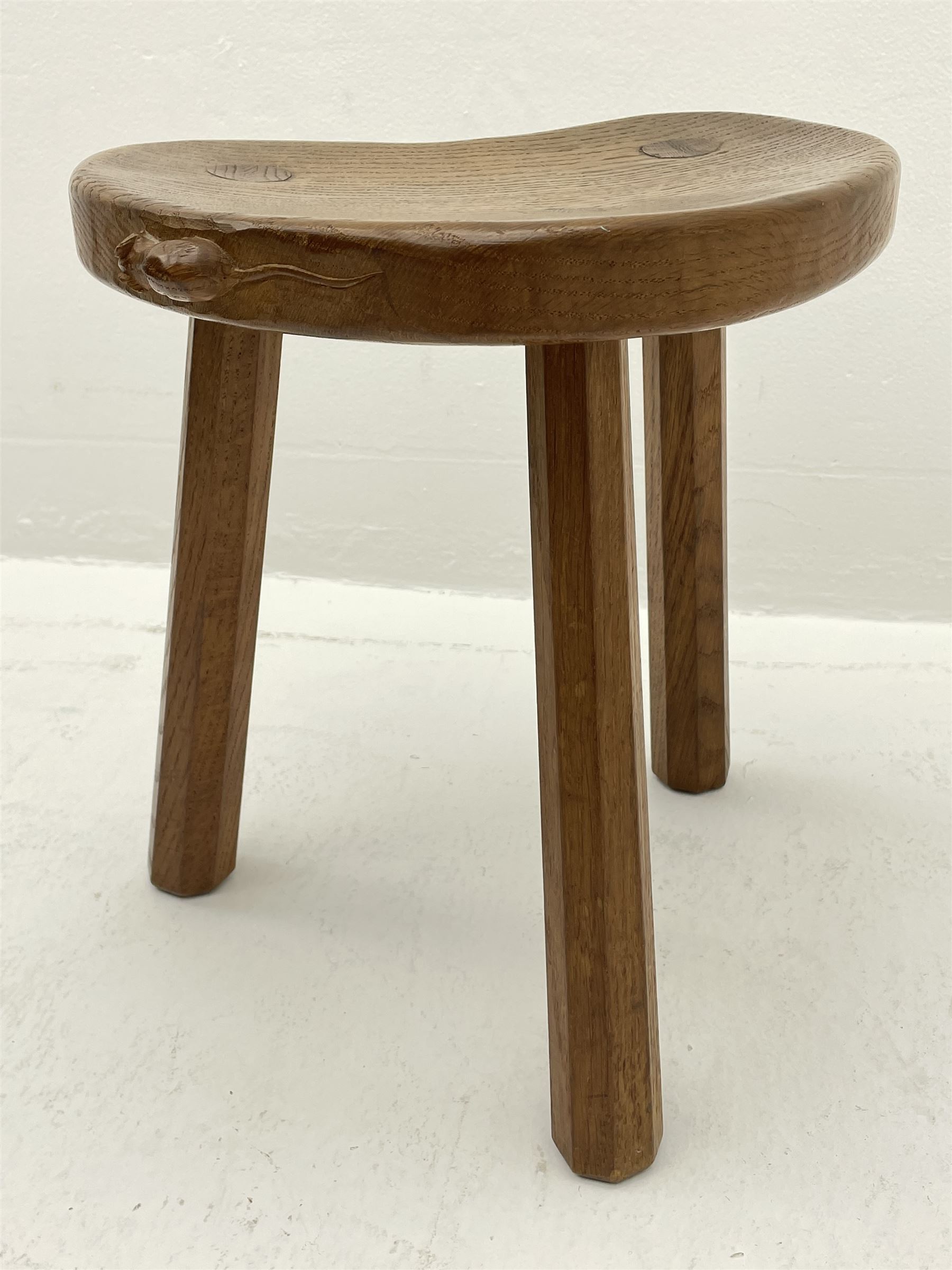 'Mouseman' oak three legged stool with dished kidney shaped seat, tapered octagonal supports, with carved mouse signature, by Robert Thompson of Kilburn 