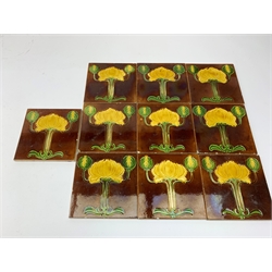 Ten Art Nouveau tiles, each decorated with stylised yellow and green flowers upon a brown ground,15cm x 15cm. 