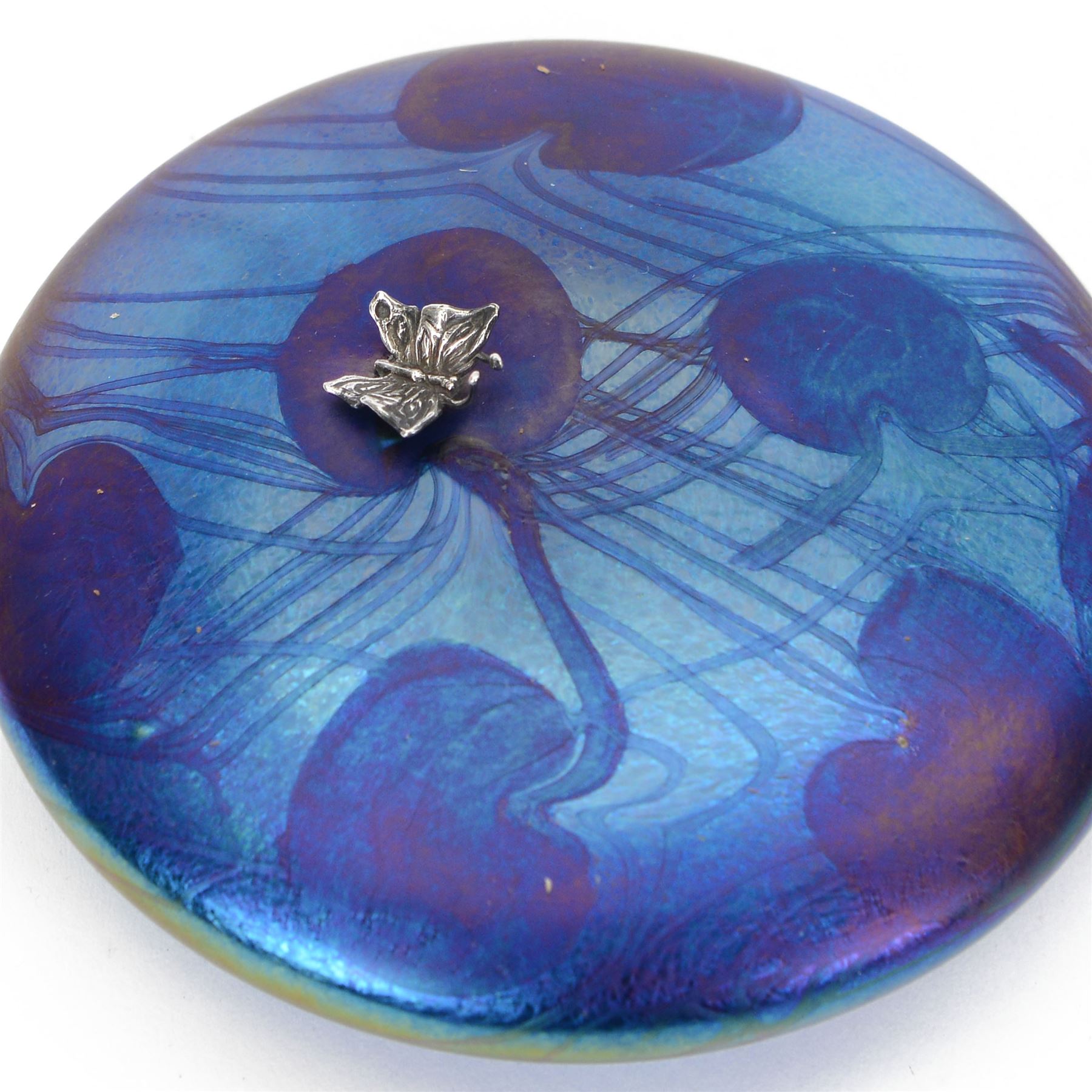 John Ditchfield for Glasform disc paperweight in iridescent blue with purple lily trail and silver hallmarked butterfly to top, D12cm