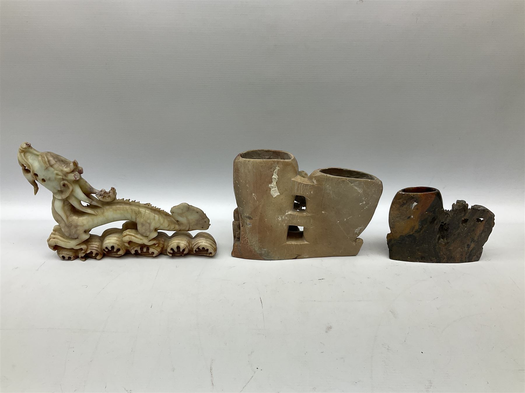 Three soapstone carvings, to include three toed dragon example, carved example with monkeys and another similar, together with carved wood figure, largest L29cm 