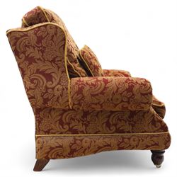 Duresta – pair of armchairs, upholstered in red and gold damask fabric with piped edges, scroll arms and loose feather-filled cushions, raised on turned wooden feet with brass castors