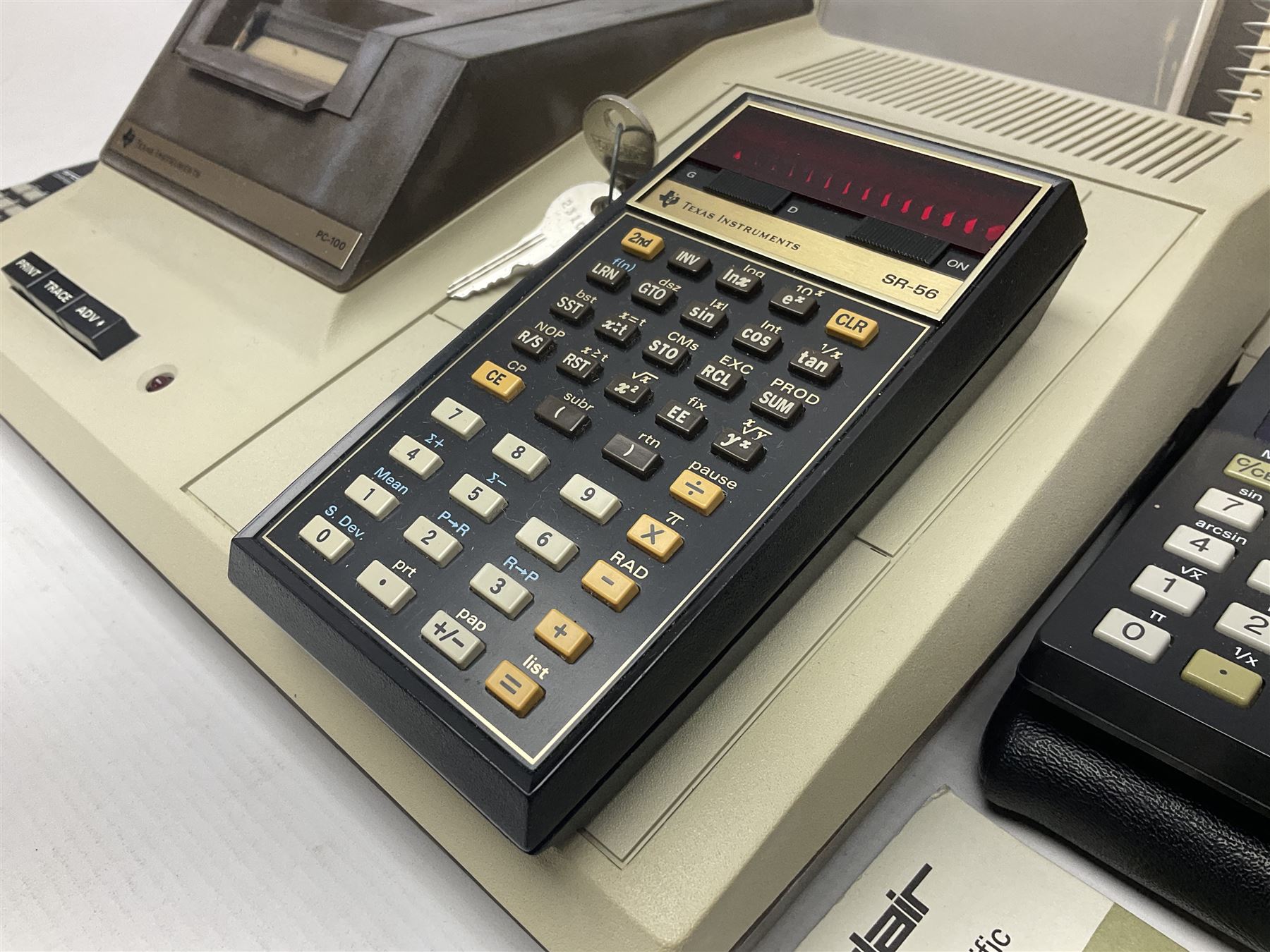 Four 1970s Sinclair electronic calculators - Cambridge in hard case with booklet; Scientific Programmable with Program Library and booklet; Scientific in hard case; and Oxford 300 in soft case with booklet; together with Texas PC-100 SR56 programmable slide-rule calculator on base station with readout, two booklets, keys and cover, serial no.9103093