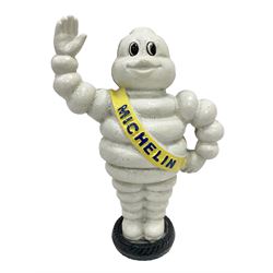 Cast iron money bank of a waving Michelin man stood on a tyre, H23cm