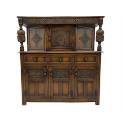 20th century carved oak court cupboard, s-scroll carved frieze over panelled cupboard door carved with arch, lobe and scroll carved cup and cover supports, fitted with three drawers and three cupboards below