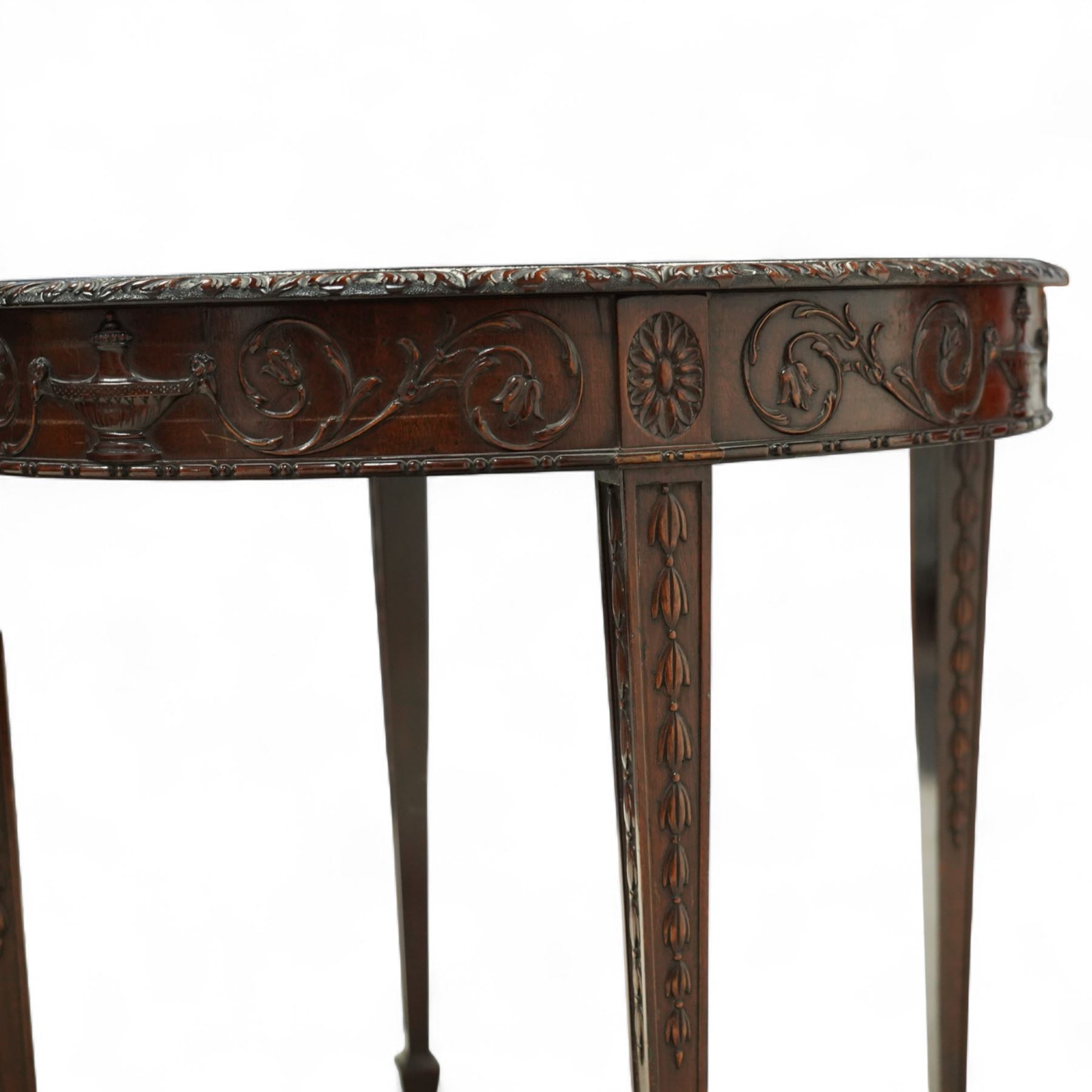 Early 20th century mahogany circular centre table in the Adams style, the moulded frieze carved with scrolling foliage and urn motifs between rosettes, raised on square tapering legs with carved husk decoration and terminating in spade feet