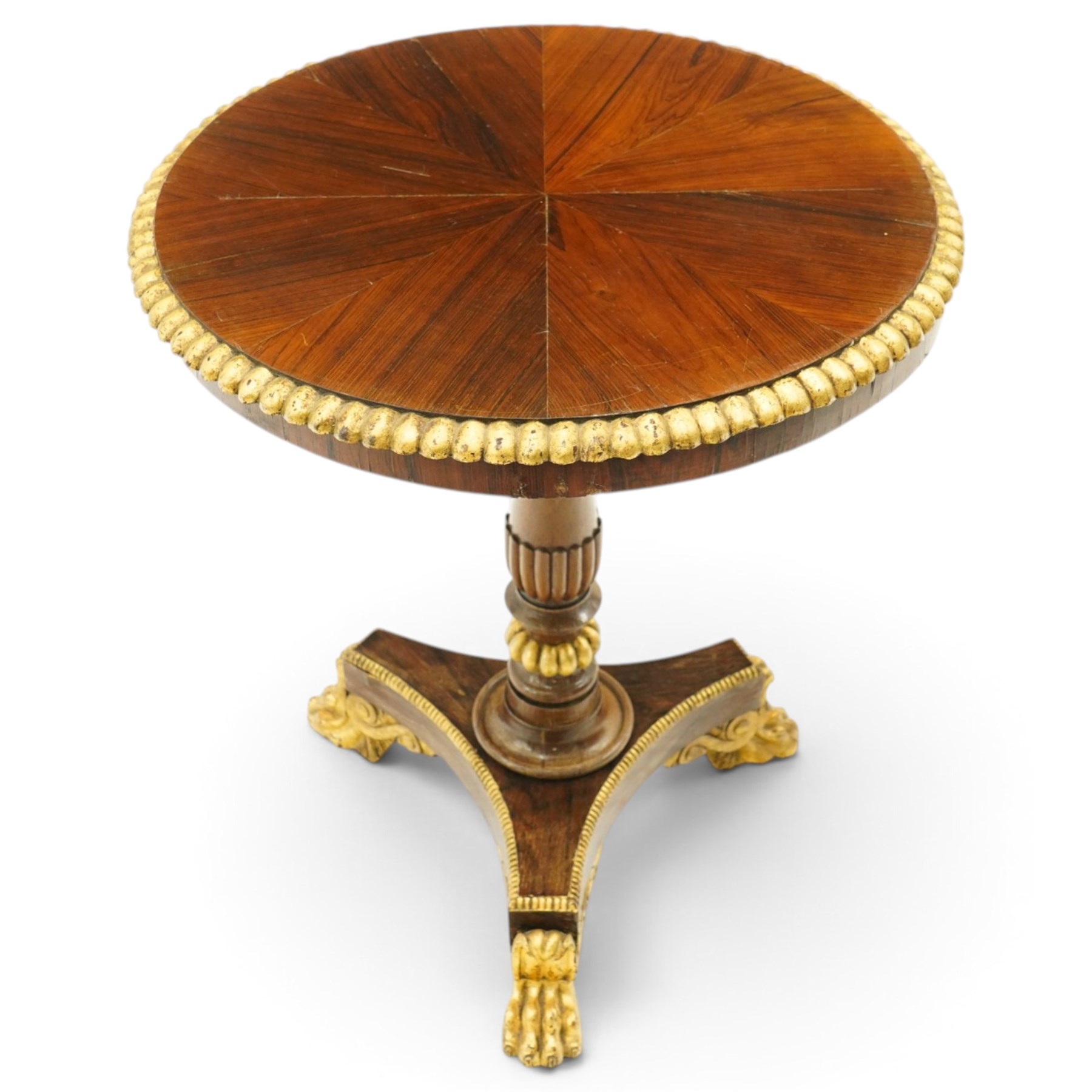 French Empire design rosewood and parcel-gilt occasional table, the circular top with sunburst veneer and giltwood gadrooned edge, raised on a turned and lobed pedestal terminating to a triform platform base with gilt beading, raised on three large paw feet with scrolling foliate brackets