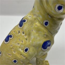 Faience model of a pug in the style of Emily Galle, naturalistically modelled, the head inset with brown glass eyes, glazed and painted with hearts and circles upon a yellow ground, GR signed to the foot, H32cm