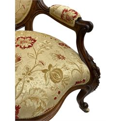 Pair of Victorian lady's and gentleman's walnut open armchair and nursing chair, shaped cresting rail carved with scrolls and flower head, upholstered in pale gold fabric decorated with floral pattern, foliate carved cabriole feet, on brass and ceramic castors 
