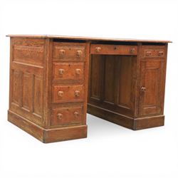 20th century oak compact pedestal desk, tooled green leather inset top, above a single frieze drawer, with a bank of four graduated drawers and a drawer and cupboard, panelled sides raised on castors