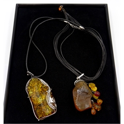  Two large silver Baltic amber set pendants, stamped 925, on leather necklaces  