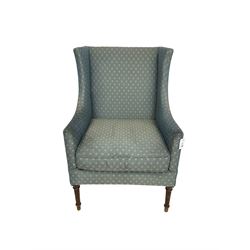 Early 20th century high wing-back armchair, upholstered in pale teal lozenge patterned fabric, raised on turned and fluted supports