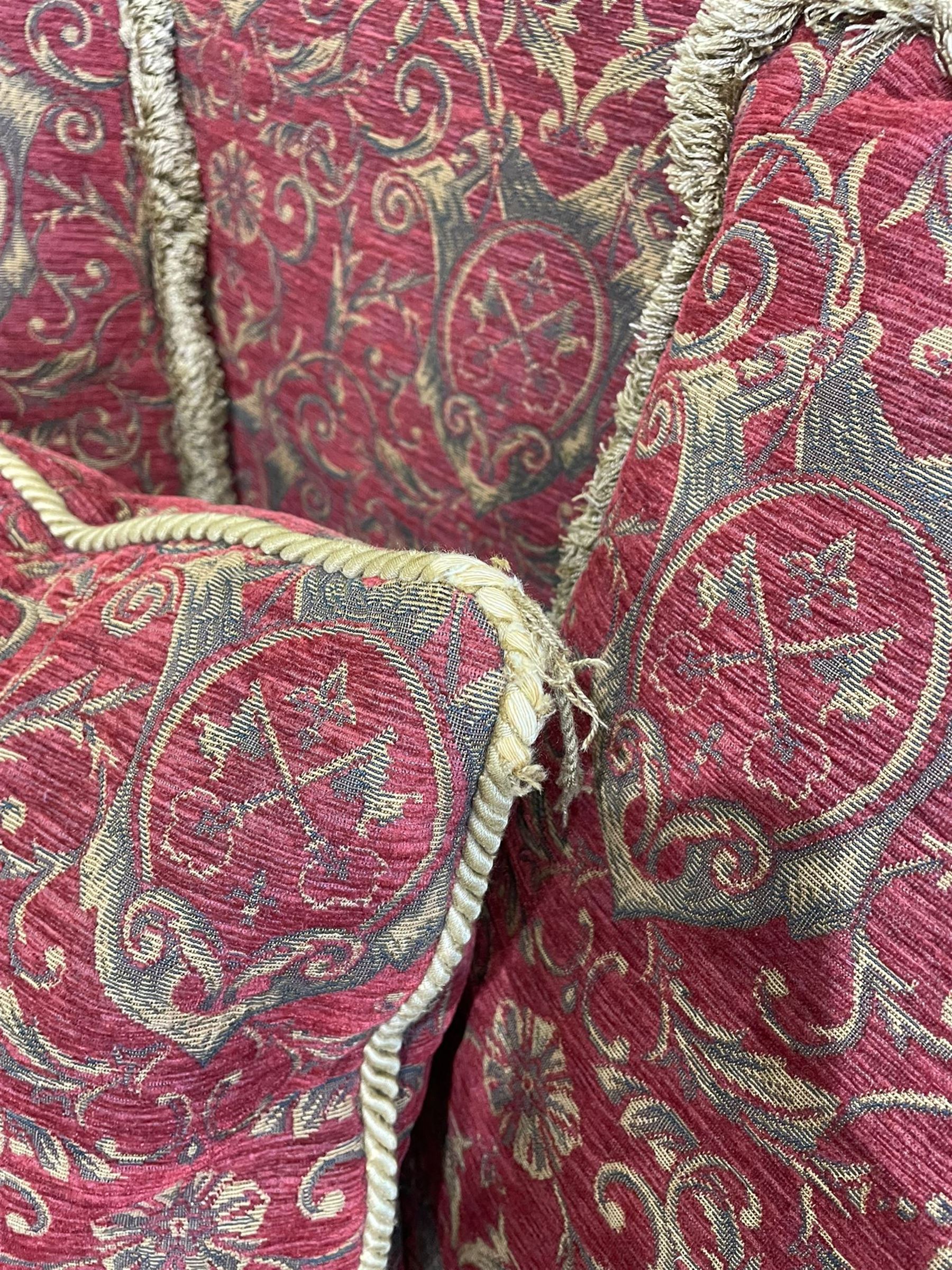 Large Knole design hardwood-framed three-seat drop-arm sofa, upholstered in crimson fabric decorated with trailing acanthus leaves and shields, together with scatter cushions 