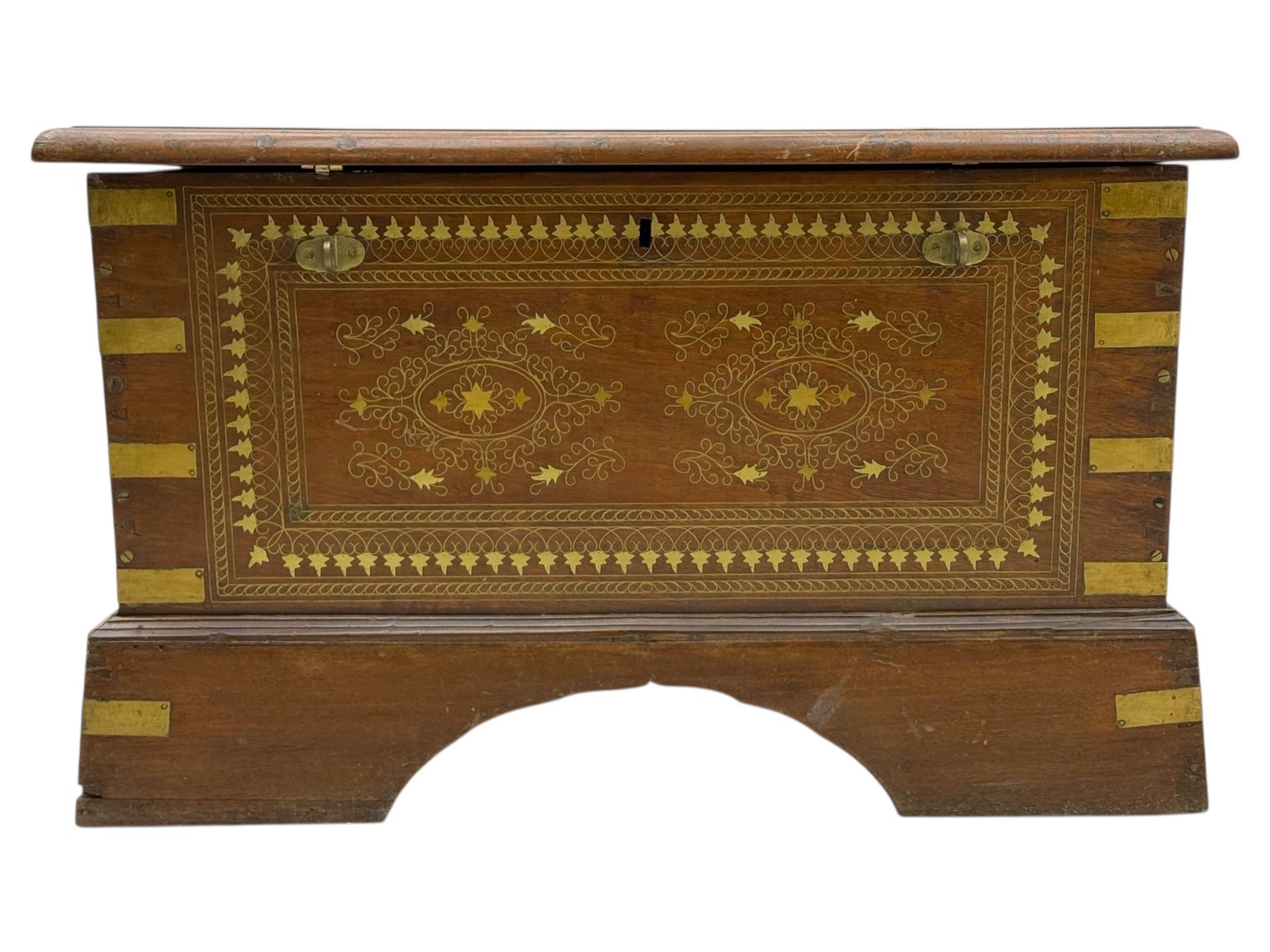 Zanzibar chest, early 20th century, of hardwood construction with brass inlaid foliate and geometric decoration to the lid, fitted interior of multiple carved compartments, with brass strapwork, side handles, and shaped bracket feet