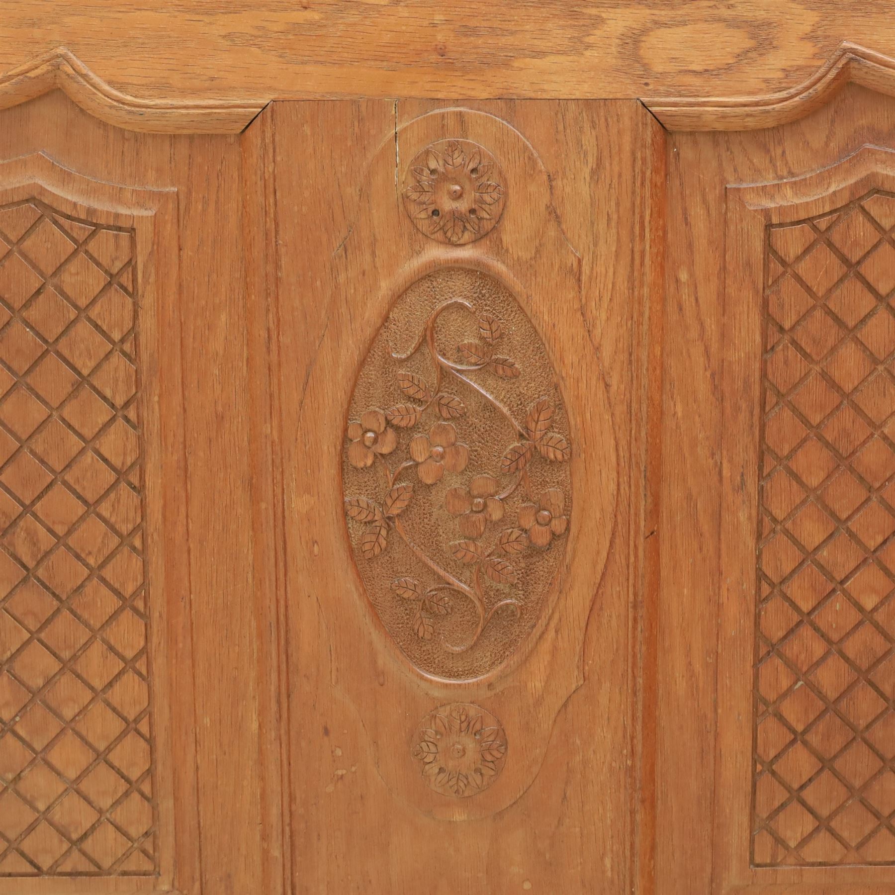 Early 20th century French oak double bedstead, the shaped and moulded headboard carved with central floral cartouche and scrolling foliage above lattice carved panels, the conforming footboard with pierced and carved decoration, shaped apron with foliate carving, raised upon cabriole supports