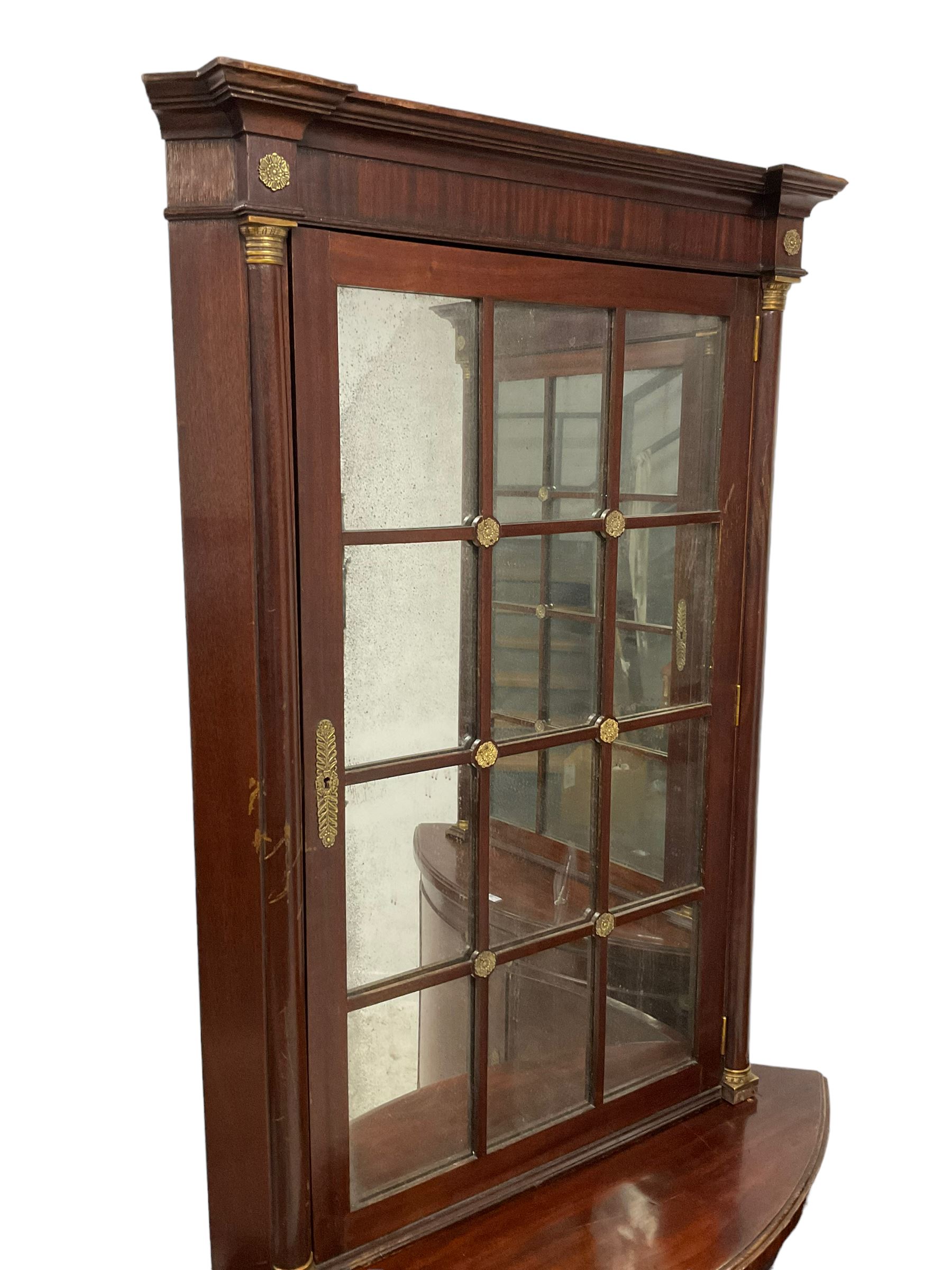Pair of French Empire design corner cabinets, the straight-front upper section with canted corners and applied half-column pilasters, enclosed by mirror glazed door, the bow-front lower section enclosed by two doors with applied mouldings, mounted by cast metal floral rosettes, skirted base with cast gilt metal hairy paw brass feet
