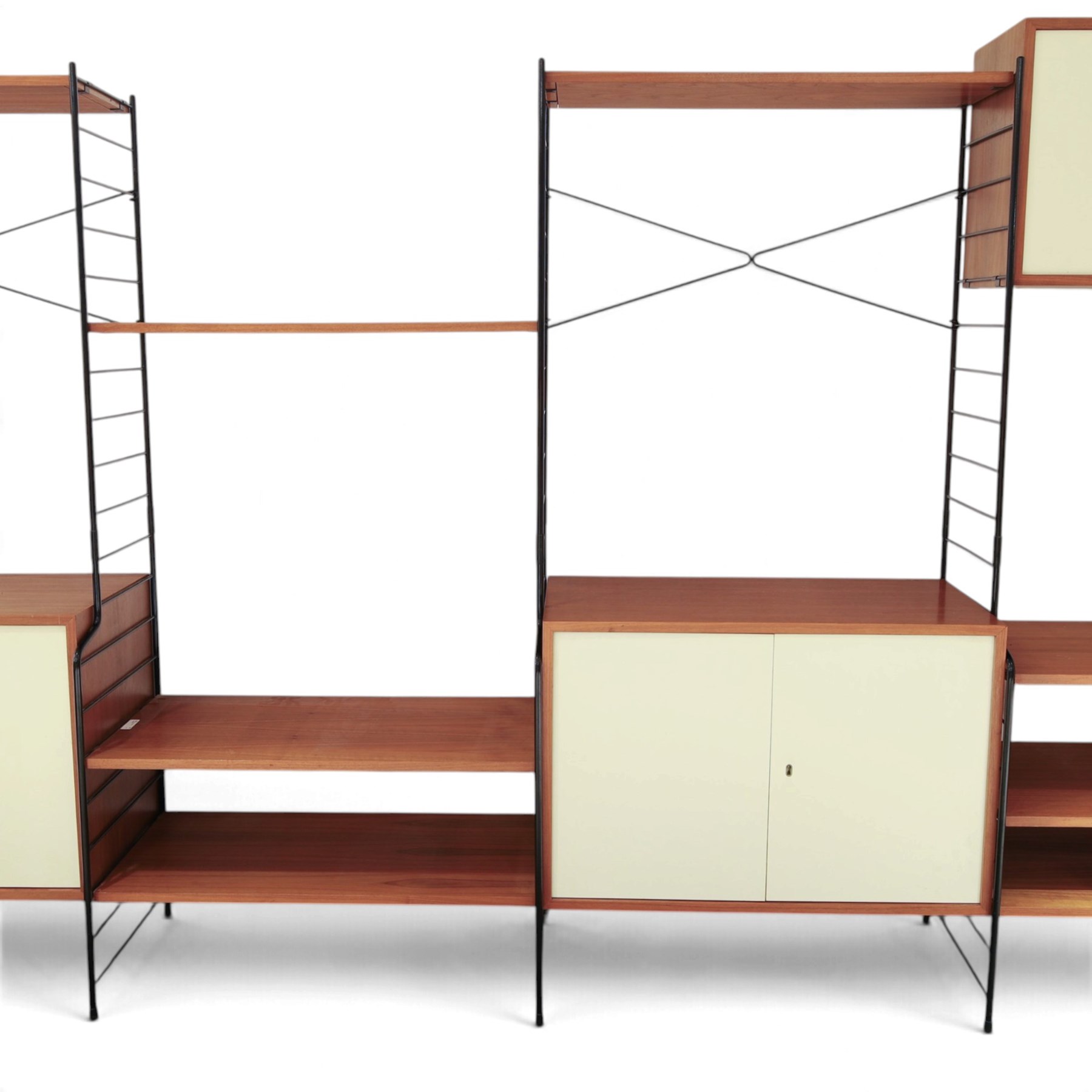 WHB - 'Ladderax' 1960s German modular shelving wall unit, comprising two teak cabinets with white doors, a further fall front teak cabinet with white front, a drawer section with three drawers with recessed handles, multiple shelving sections, raised on metal ladder frames, with further spare sections

Cabinet units: H 47cm, D 36cm, W 71cm
Fall front unit: H 40cm, D 26cm, W 71cm
Shelve widths: 50cm, 71cm 
Shelve depths: 26cm, 36cm
