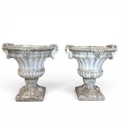 Pair of Neoclassical design cast stone garden urns, each of campana form with fluted body and gadrooned underbelly, decorated with faun/satyr opposing masks and ropetwist handles, with floral and mask design to the socles, raised on square bases, finished in weathered white patina