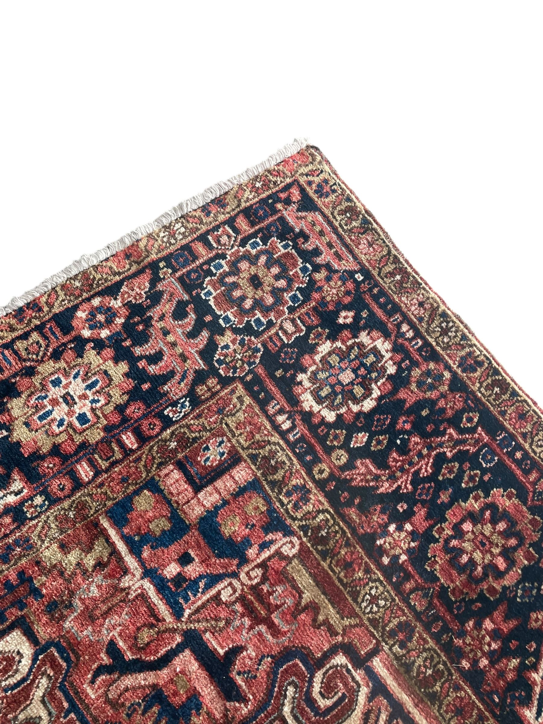 Persian Heriz red ground carpet, large stylised pole medallion surrounded by Pitrak motifs, indigo ground border decorated with stylised flower heads and trailing leafy branches, within floral pattern guard stripes