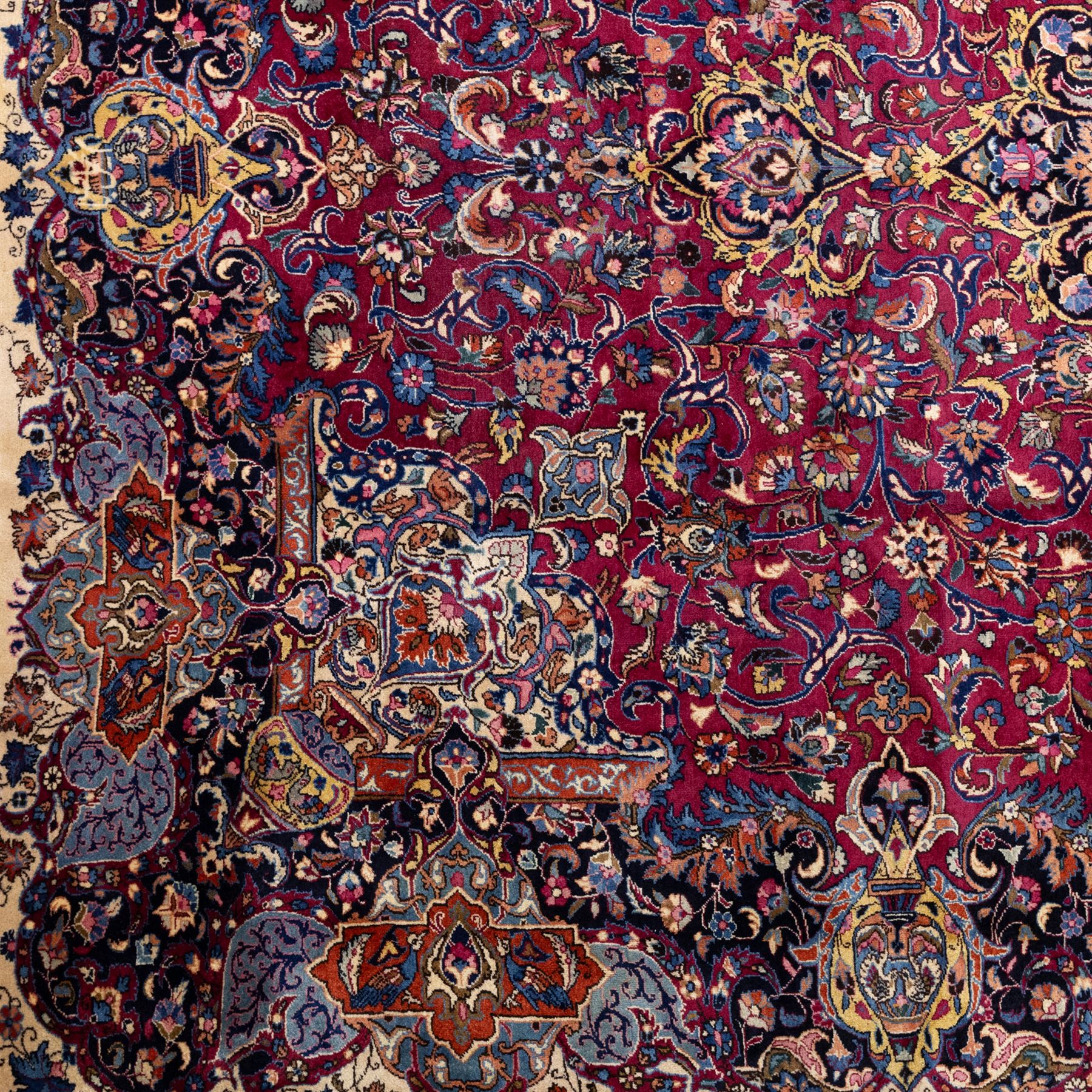 Large North East Persian Meshed hand-knotted carpet with signature, raspberry red field with central shaped cusped medallion, densely decorated with intricate arrangement of scrolling vines, and florals designs within conforming spandrels and a dark ground border richly ornamented with stylized flowers, vase and bird ornamentation, enclosed by guard stripes, with cotton fringe ends