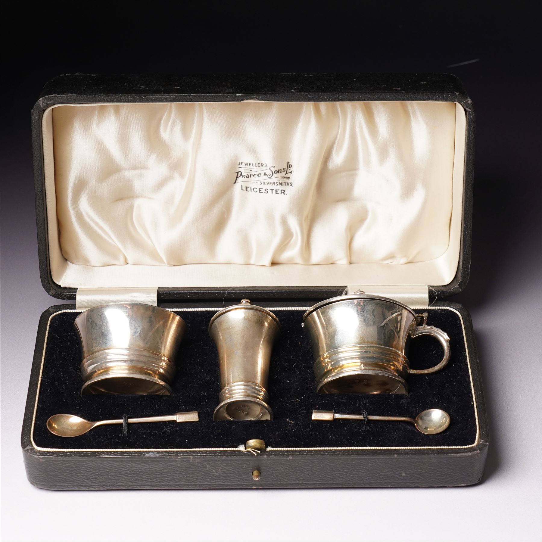 Silver three piece condiment set of circular design and two original spoons, cased Birmingham 1937-1939 Maker Deakin & Francis Ltd 