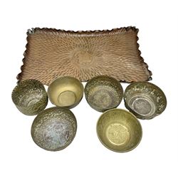 Beaten copper tray with repeat pattern and fluted rim, together with six brass cups, tray L41cm 