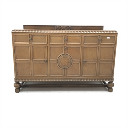 E. Gomme Ltd of High Wycombe oak sideboard, raised carved back, moulded top, three drawers above two cupboards flanking single fall front unit, turned supports joined by stretchers, W150cm, H101cm, D57cm