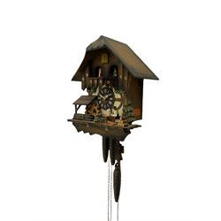 A 20th century West German 30-hour Automaton musical cuckoo clock with a Swiss musical movement playing three tunes, visible pendulum and three cast metal pine cone weights, carved pine wood case with automaton water wheel, woodsman and carousel, chapter ring with Roman numerals and decorative hands, with strike/silence lever.

