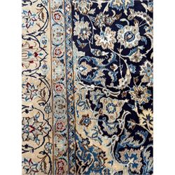 Central Persian Nain carpet, the deep blue field with finely drawn scrolling palmettes and flowering vines around a central ivory and sky blue rosette medallion, enclosed by an ivory border of interlaced floral arabesques and lotus forms between multiple guard stripes, from the region of Nain