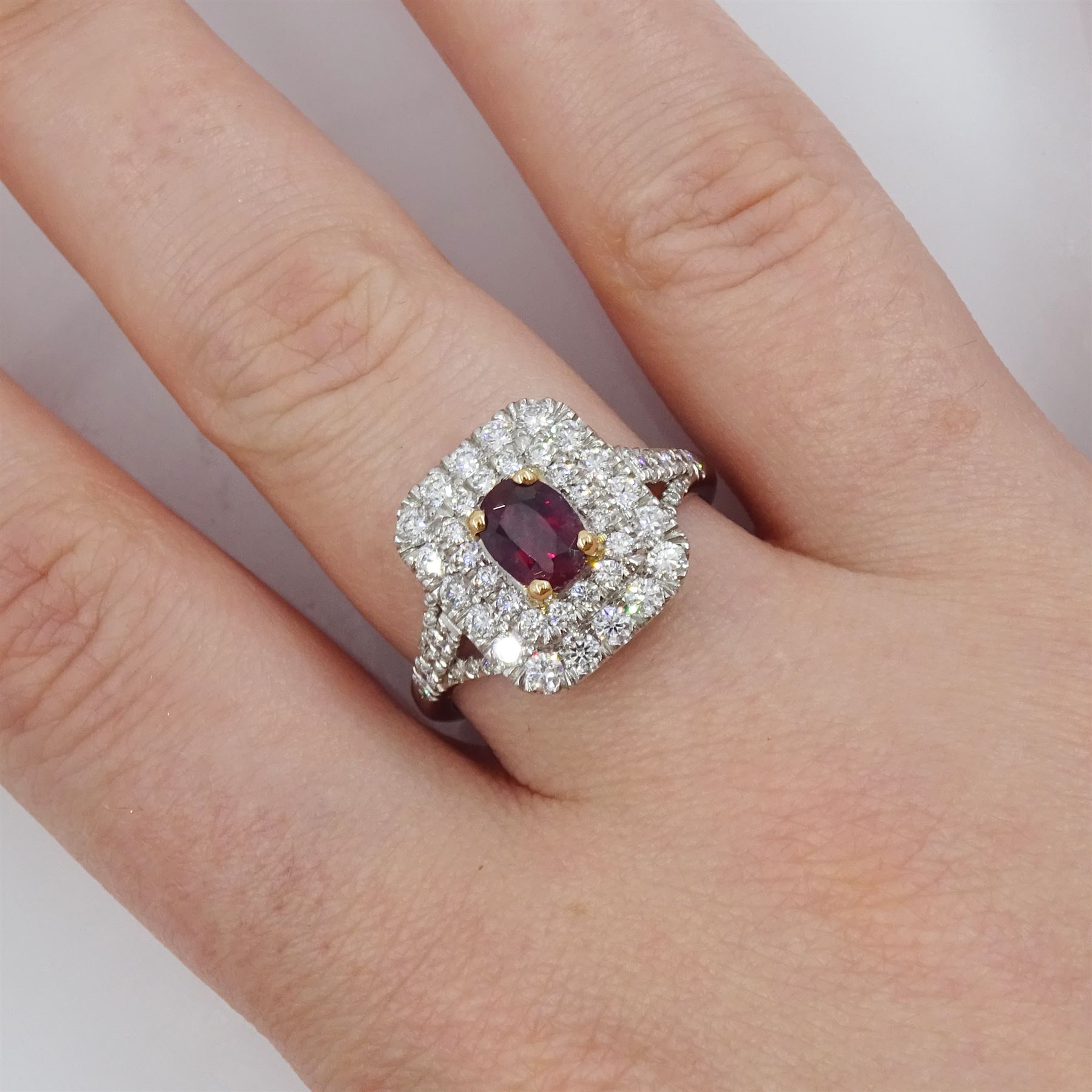 Platinum ruby diamond cluster ring, single oval cut ruby  in a four claw 18ct rose gold setting of approx 1.02 carat, surrounded by two rows of round brilliant cut diamonds and split diamond set shoulders, London 2017, total diamond weight approx 0.76 carat, with Alan Poultney Gems report