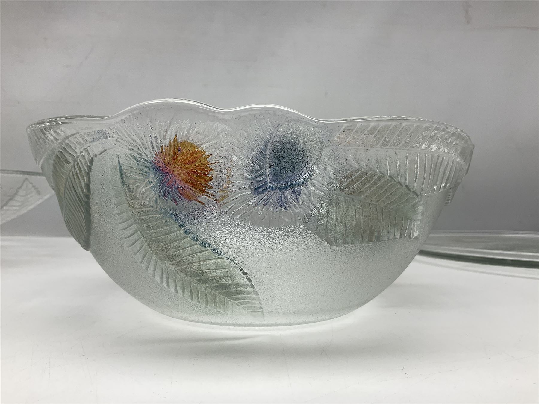 Two French pressed glass bowls of shallow circular form, relief moulded with flowers and foliage, together with a matching charger, largest bowl D34cm  