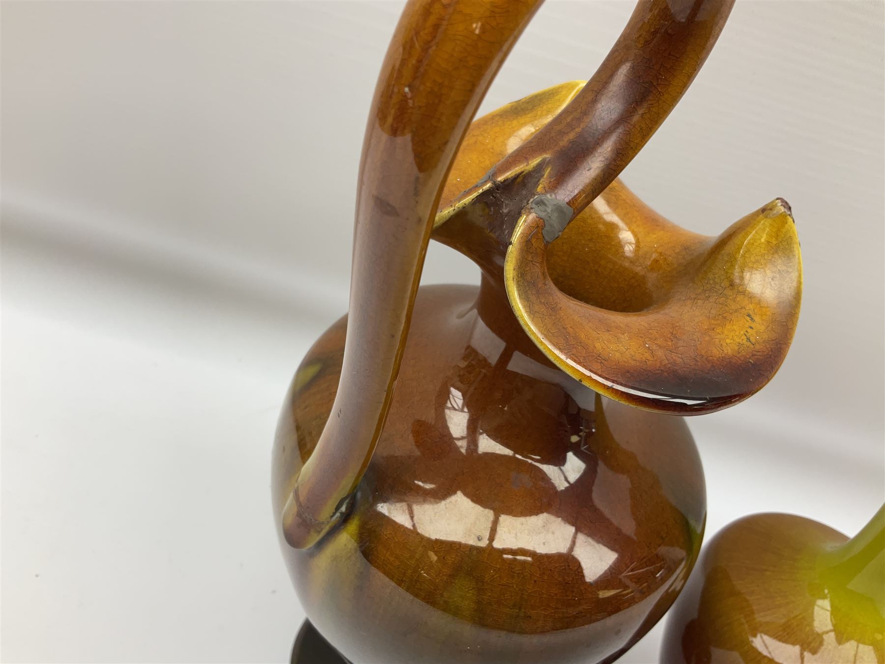 Linthorpe pottery vase with crimped rim and ovoid body, Linthorpe jug with high loop handle and crimped spout, a pair of candlesticks with a green, brown glaze and other similar pottery 