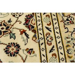 Central Persian Kashan hand-knotted carpet, ivory field with central lobed medallion issuing an all-over design of scrolling vines, palmettes, and floral sprays, within conforming spandrels, enclosed by a foliate border, framed by multiped guard stripes, with cotton fringe ends 
