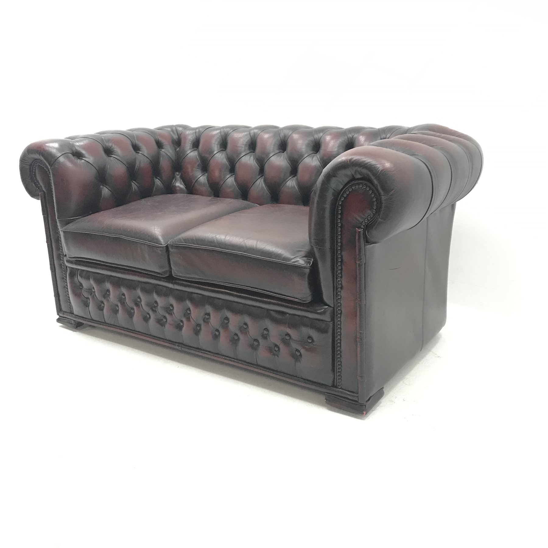 Two seat chesterfield sofa upholstered in deep buttoned ox blood