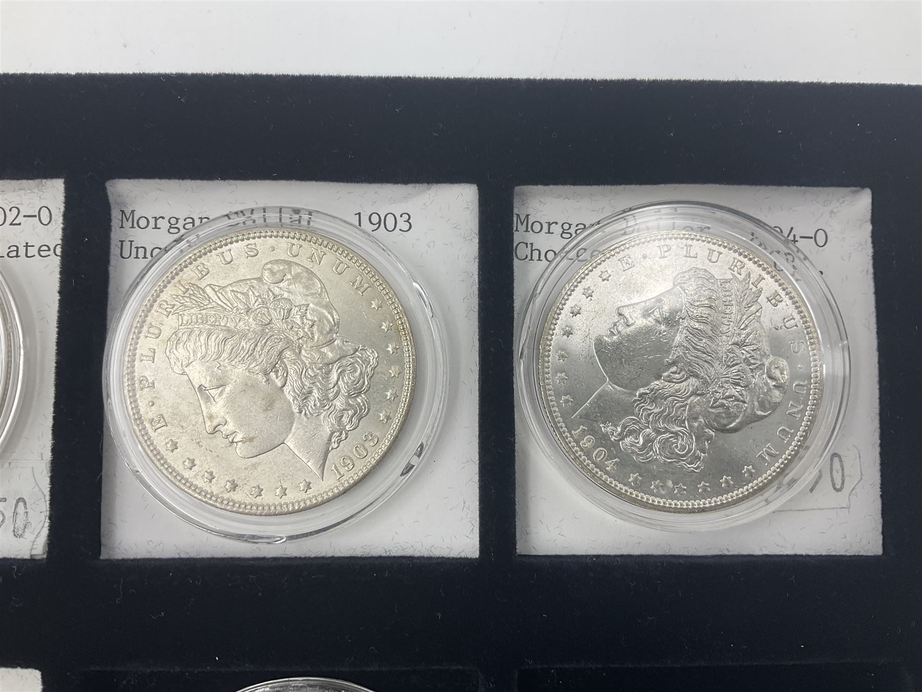 Seven United States of America silver Morgan dollar coins, dated 1884, 1901 O, 1902 O, 1903, 1904 O, 1921 D and 1921