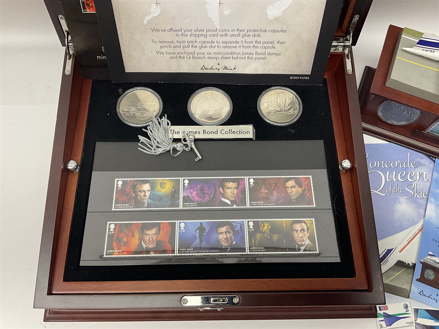 Danbury Mint 'The Ultimate James Bond Collection' comprising stamps and coins housed in a display case, 'Concorde Queen of the Skies' sculpture, stamps, medallion display and 2020 'Centenary of the Unknown Warrior' five pound coin cover in Harrington and Byrne folder