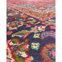 Pair of Persian wool rugs, each with rich red ground, one centred with a diamond-shaped medallion and navy spandrels within a floral field, the other with radiating floral medallion and scrolling foliate motifs, both enclosed by multiple borders with palmette and flowerhead designs, from the region of Kashan 291x376, 299 x 378 