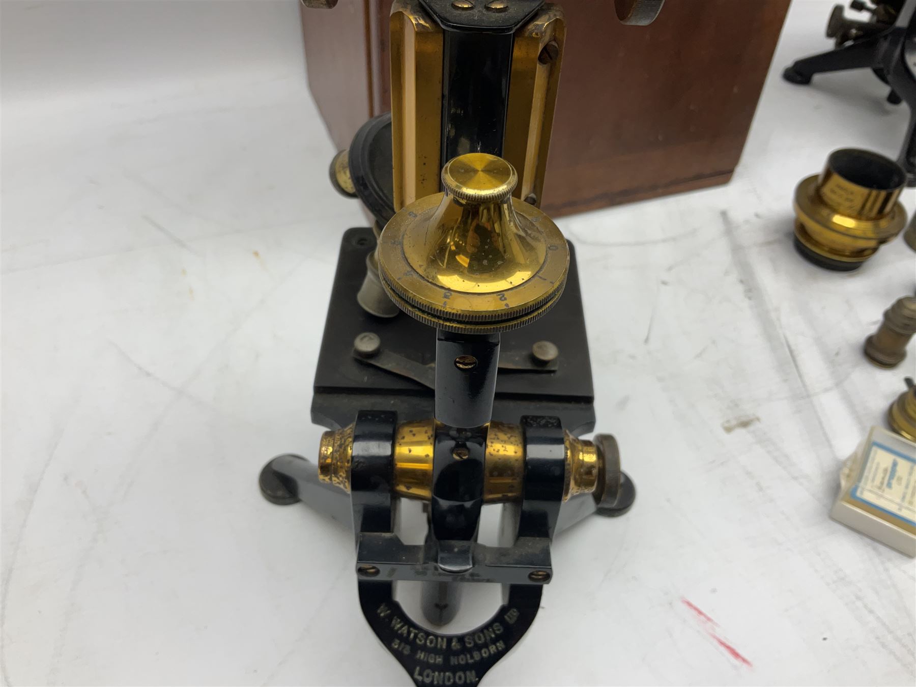 19th century brass and black japanned monocular microscope by W. Watson & Sons Ltd. 313 High Holborn, London serial no.24788 with rack and pinion focussing on tripod base H31cm; in fitted mahogany case retailed by A.H. Baird Scientific Instrument Makers Edinburgh; quantity of additional lenses and accessories; together with another similar uncased monocular microscope by W. Watson serial no.58379 (2)
