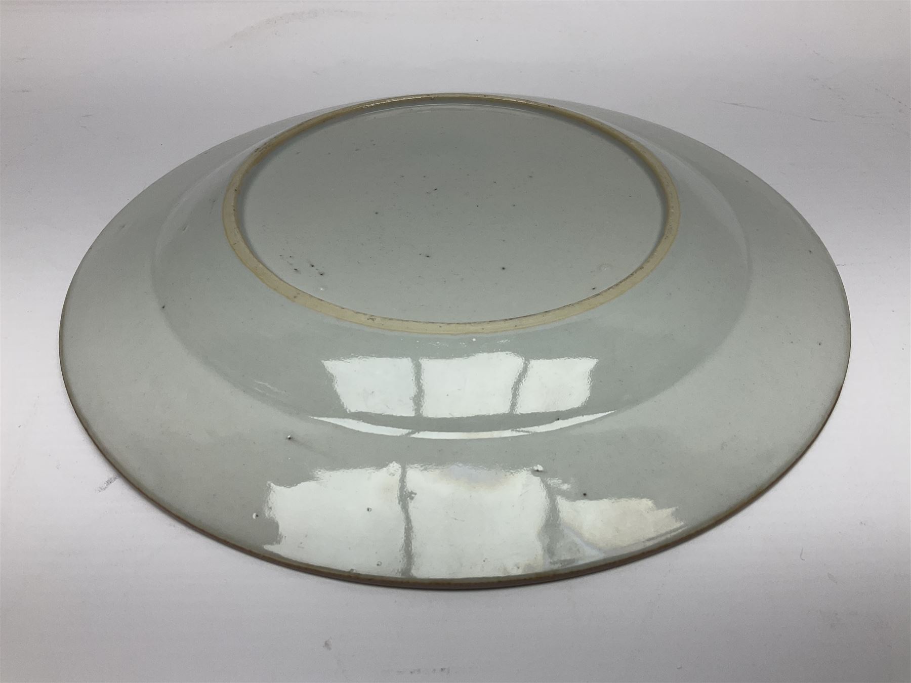 Three 18th century Chinese Famille Rose plates, the first example enamelled with blossoming peonies, rockwork and fence, the other two examples of similar design, decorated with blossoming peonies and sprigs within shaped inner borders, each approximately D23cm