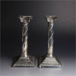 Pair of Edwardian silver mounted column candlesticks, each with embossed floral, foliate and scrolling decoration and upon stepped square weighted bases, hallmarked William Hutton & Sons Ltd, London 1901, H19cm