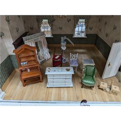 Two modern three storey dolls houses, each painted green with decorated interiors, both upon a single white wooden base, together with a large collection of dolls house furniture, accessories and figures 