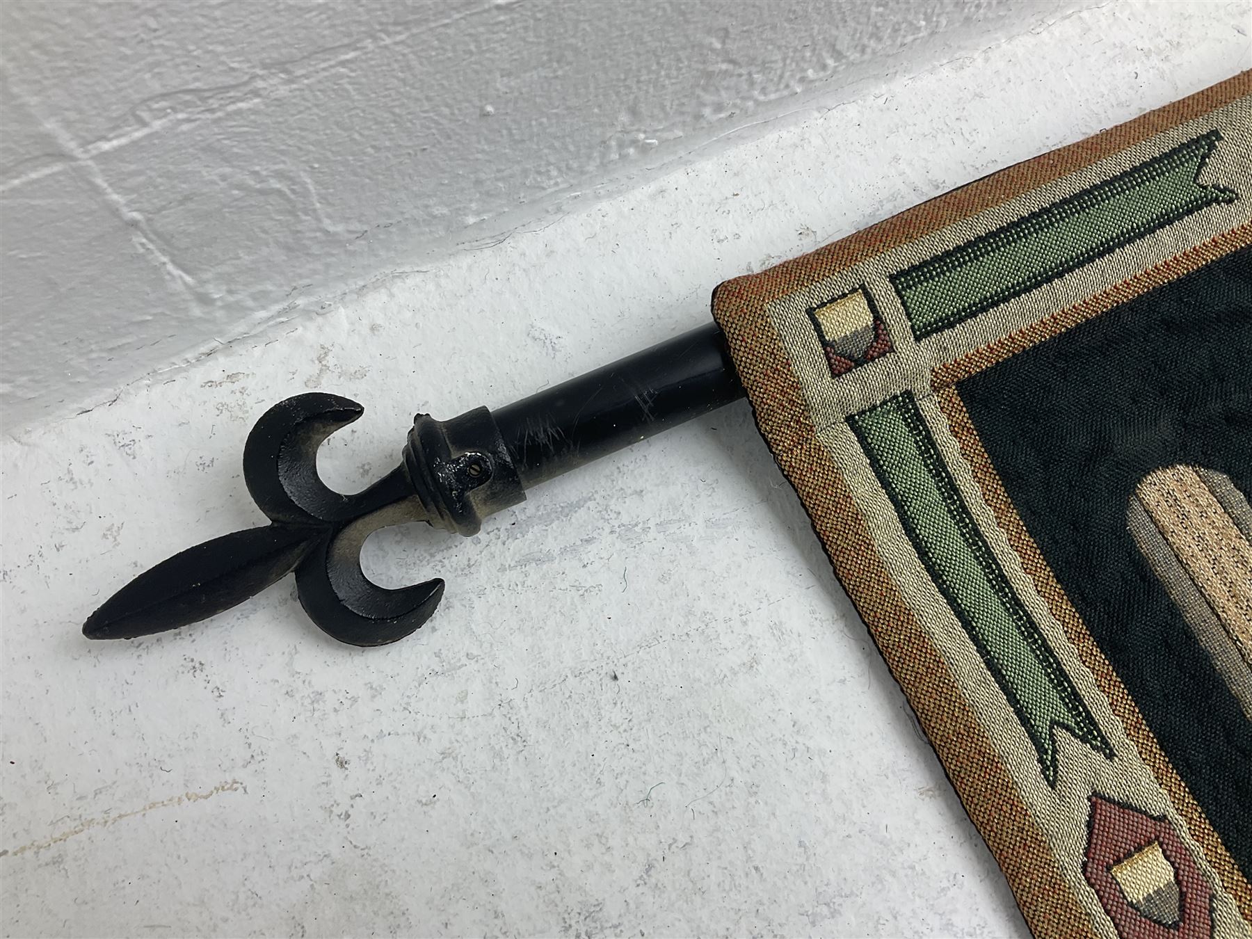 Three tapestries comprising 20th century wool tapestry panel of a medieval nobleman upon a horse with a castle in the distance, together with a smaller tapestry depicting The English Coat of Arms, both hung on rails, and further depicting village scene, largest approx 132cm x 95cm