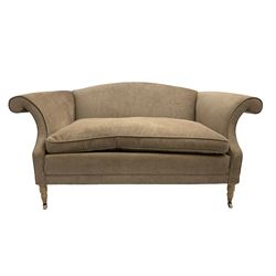 Traditional two seat sofa, curved back over scrolled arms, upholstered in crushed beige fabric with matching loose cushions, on turned front supports with brass and ceramic castors