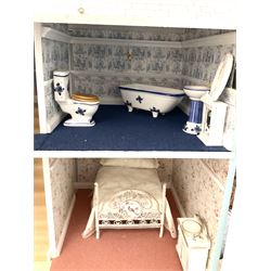 Georgian style wooden double fronted three-storey dolls house with pale blue stucco finish under a faux tiled roof with two chimney stacks, the double hinged front opening to reveal six fully decorated rooms with floor coverings, central staircase, porcelain fitted bathroom, kitchen with deep white sink and Aga cooker, electric lighting with adaptor, fully furnished with French style and other furniture, grand piano etc, and comprehensive range of accessories H82cm W61cm D31cm