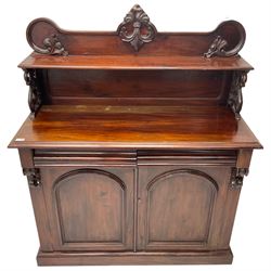 Victorian mahogany chiffonier, raised shaped back with foliage scroll carved mounts, on fretwork and carved bracket supports, moulded rectangular top over two frieze drawers and double panelled cupboard, on moulded plinth base