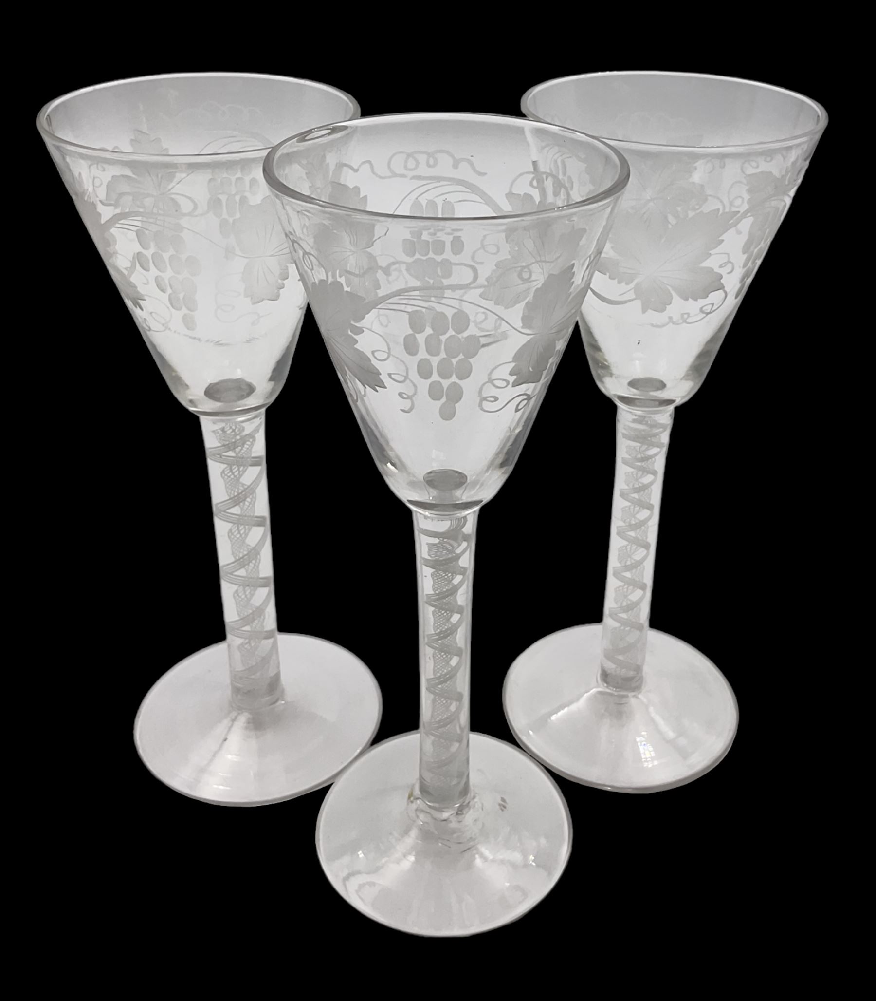 Set of three 18th century style wine glasses, each with funnel bowl etched with fruit vine, upon a double series air twist stem and circular foot, H17cm